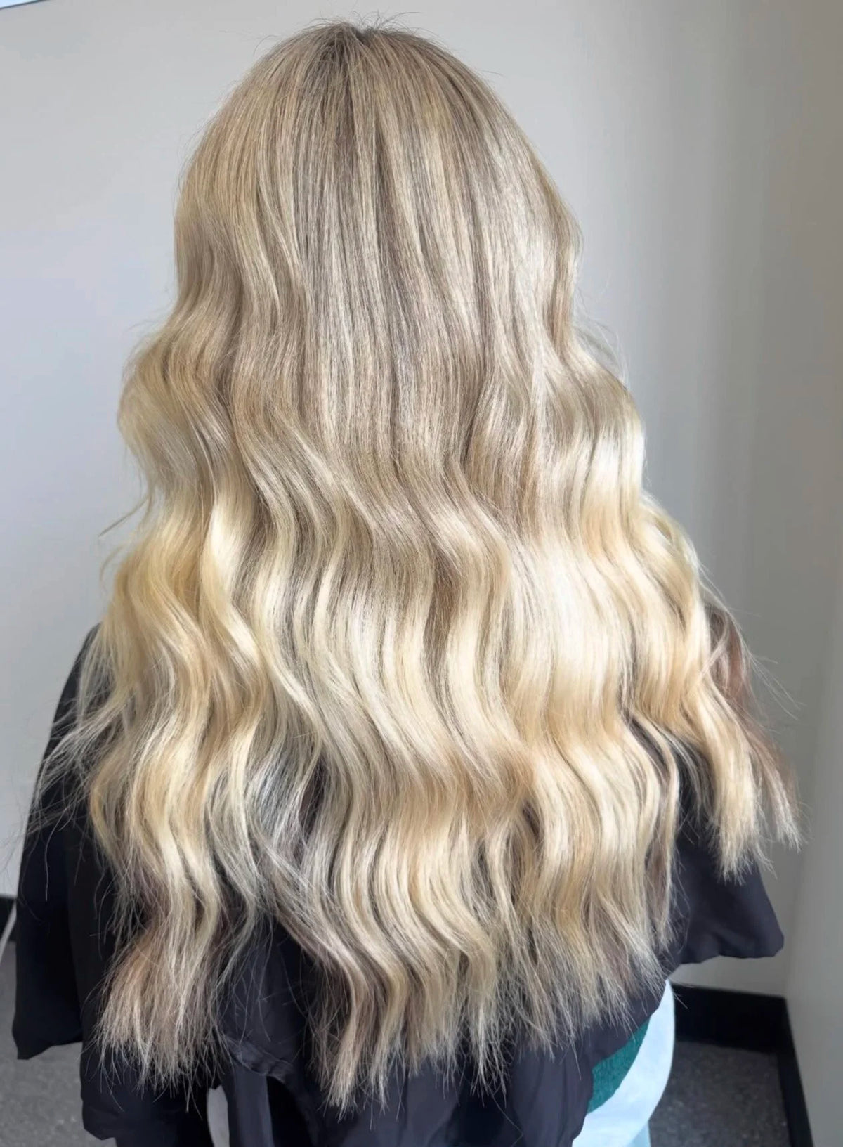 Long blonde hair with a blended root styled in loose waves at Oh Baby Salon & Spa in Bloomington, Illinois