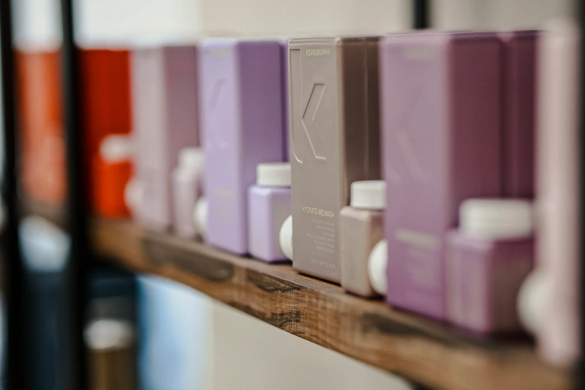 Purple and gray hair care bottles on a wooden shelf at Oh Baby Salon and Spa in Bloomington, Illinois